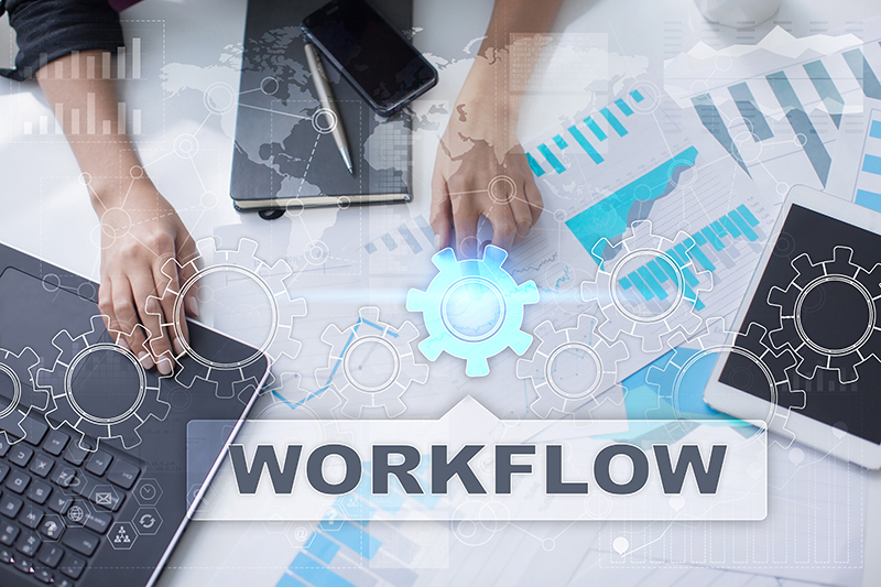 workflow with cogs, graphs, hands & laptop viewed from above